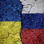 Cracked Ukrainian and Russian flags painted on concrete.