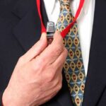 Person holding a whistle on a red lanyard.
