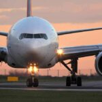 Airplane on runway at sunset, front view.