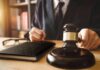 Gavel judges hand glasses and book on desk