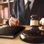 Gavel judges hand glasses and book on desk