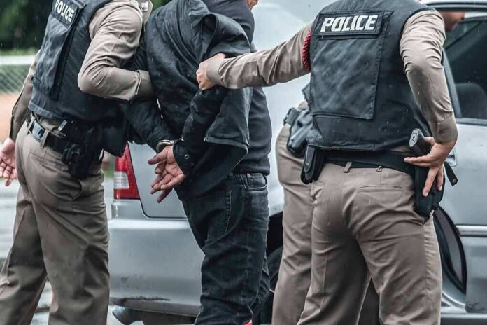 1137889661 featured image Police arresting a person by a car.