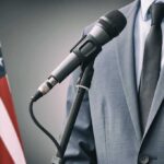 Hakeem Jeffries Faces New Challenges Leading Democrats Post-Pelosi Era Man in suit speaking into microphone, standing next to American flag.