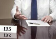 IRS official gesturing, with documents and pen.