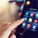Finger tapping social media app icons on a smartphone.