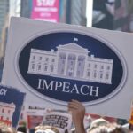 Protesters hold signs calling for impeachment