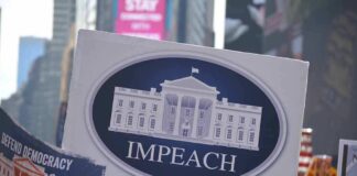 Protesters hold signs calling for impeachment