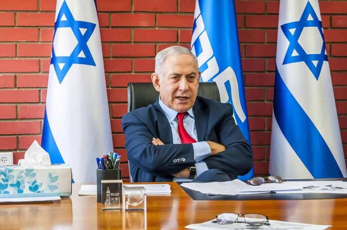 1564752907 featured image Man sitting at desk with Israeli flags behind.