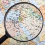 Magnifying glass focused on the Middle East map.