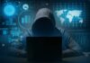 Hacker in hoodie using laptop with digital graphs