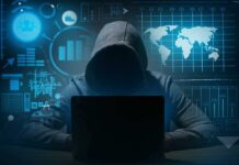 Hacker in hoodie using laptop with digital graphs
