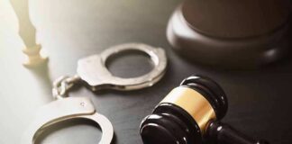 Handcuffs beside a judges gavel on dark surface