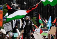 Protesters with flags and signs one holding a megaphone