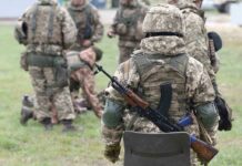 Soldiers in camouflage gear gathered on grass field
