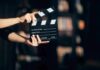 Hands holding a film clapperboard against a dark background