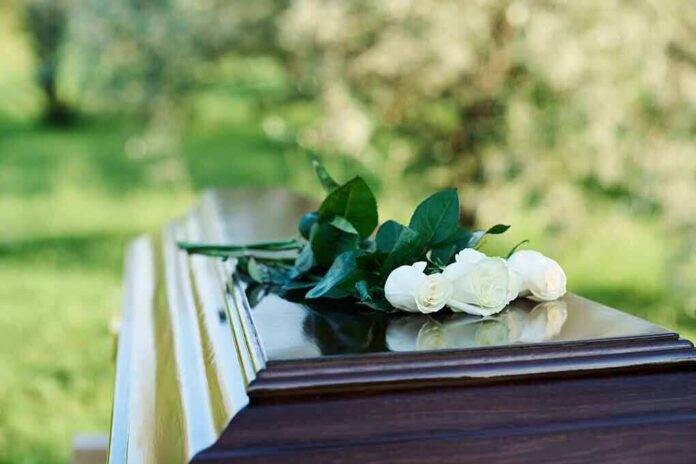 2360876193 featured image White roses on a polished wooden casket outdoors.