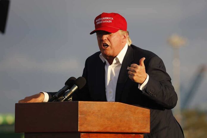 318051161 featured image Person speaking at a podium wearing a red hat.