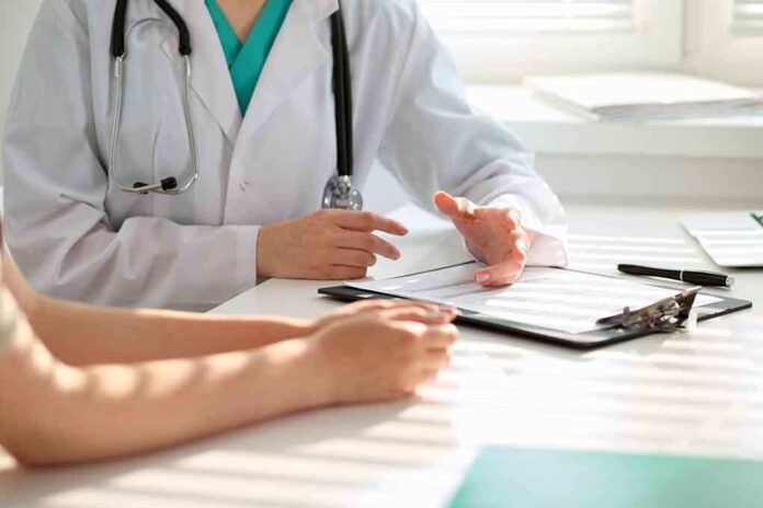 50075309 featured image Doctor discussing with patient, holding clipboard on desk.