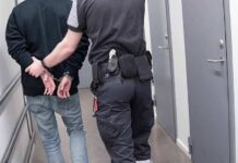 Officer escorting handcuffed person down hallway