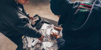 Two individuals handling stacks of money on a table