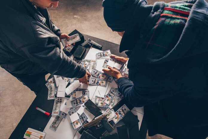 1283218267 featured image Two individuals handling stacks of money on a table