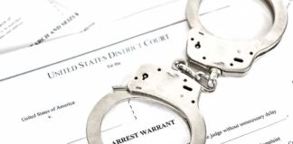 Handcuffs placed on an arrest warrant document
