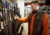 Man examining rifles in a store