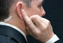Man wearing an earpiece, touching his ear