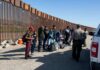 Group of people at border wall with patrol agents