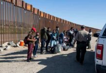 Group of people at border wall with patrol agents