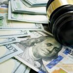 Gavel and hundred dollar bills on table