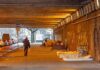 People walk under a bridge with homeless encampment