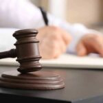 Judge's gavel on desk with person writing
