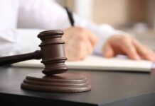 Judge's gavel on desk with person writing