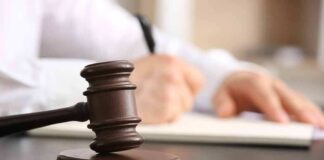 Judge's gavel on desk with person writing