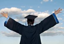 Graduate in cap and gown celebrates under cloudy sky