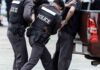 Police officers arresting a handcuffed person