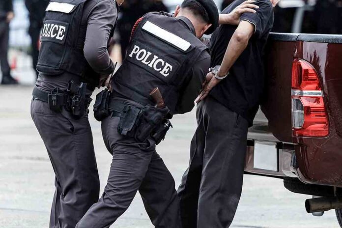 Police officers arresting a handcuffed person
