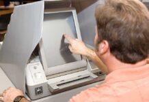 Person using touchscreen voting machine in polling booth
