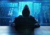 Person in hoodie using a laptop with digital code