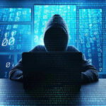 Person in hoodie using a laptop with digital code