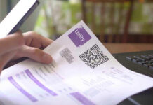 Hand holding utility bill with QR code