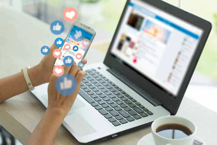 1573945981 Person using smartphone and laptop with social media icons