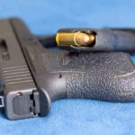 Handgun on blue fabric with visible bullet cartridge