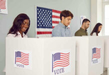 People voting in booths with American flag backdrop