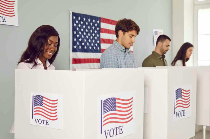 2360884499 People voting in booths with American flag backdrop