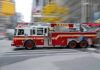 Red fire truck driving through city street crosswalk