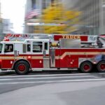 Red fire truck driving through city street crosswalk