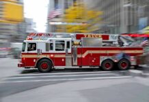 Red fire truck driving through city street crosswalk