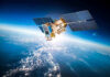 Satellite orbiting Earth with moon in background